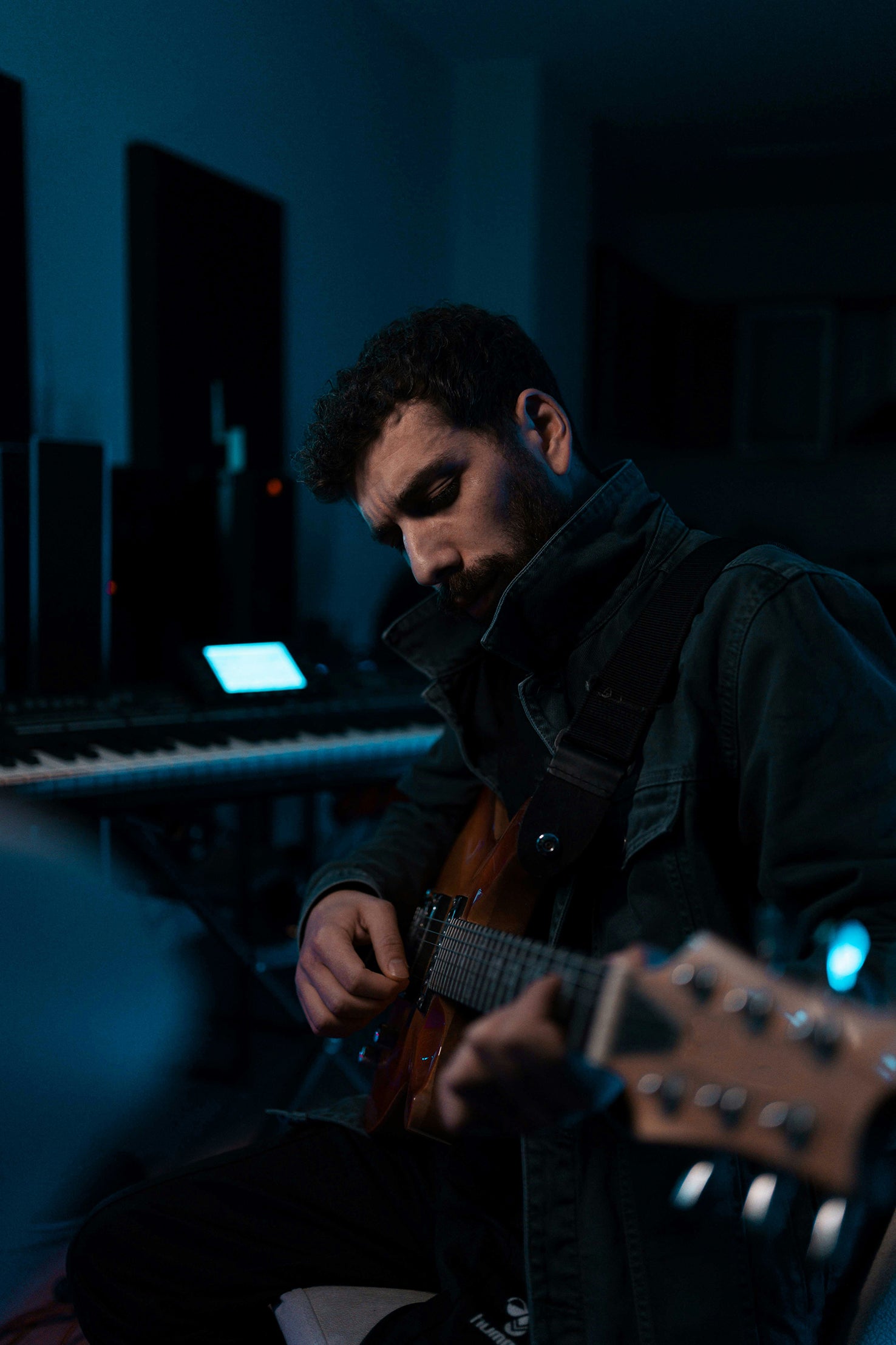 Rock Musiker in dunklem Raum mit blauem Licht und Gitarre